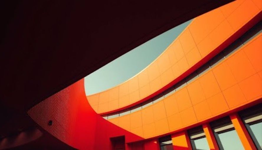 Curving orange building with blue sky background