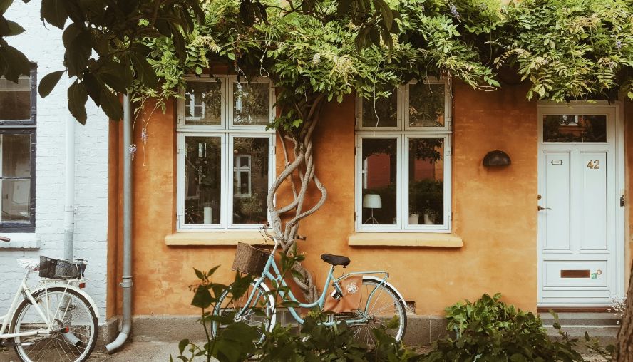 Bike leaning against the wall of an orange house.