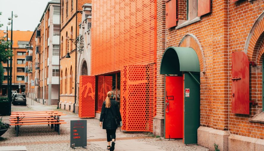 Women walking past an orange building in an urban landscape